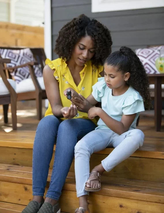 Eine Mutter und ihre Tochter sitzen auf einer Treppe und testen die Ätherischen Öle.