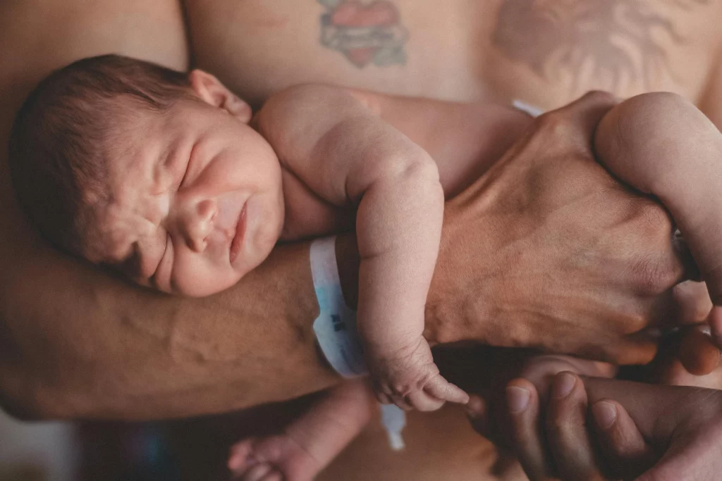 Vater hält nach der Geburt sein Baby in seinem Arm.