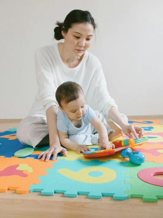 Das Baby erhält viele Geschenke. Mutter und Baby spielen zusammen mit den neuen Geschenken.