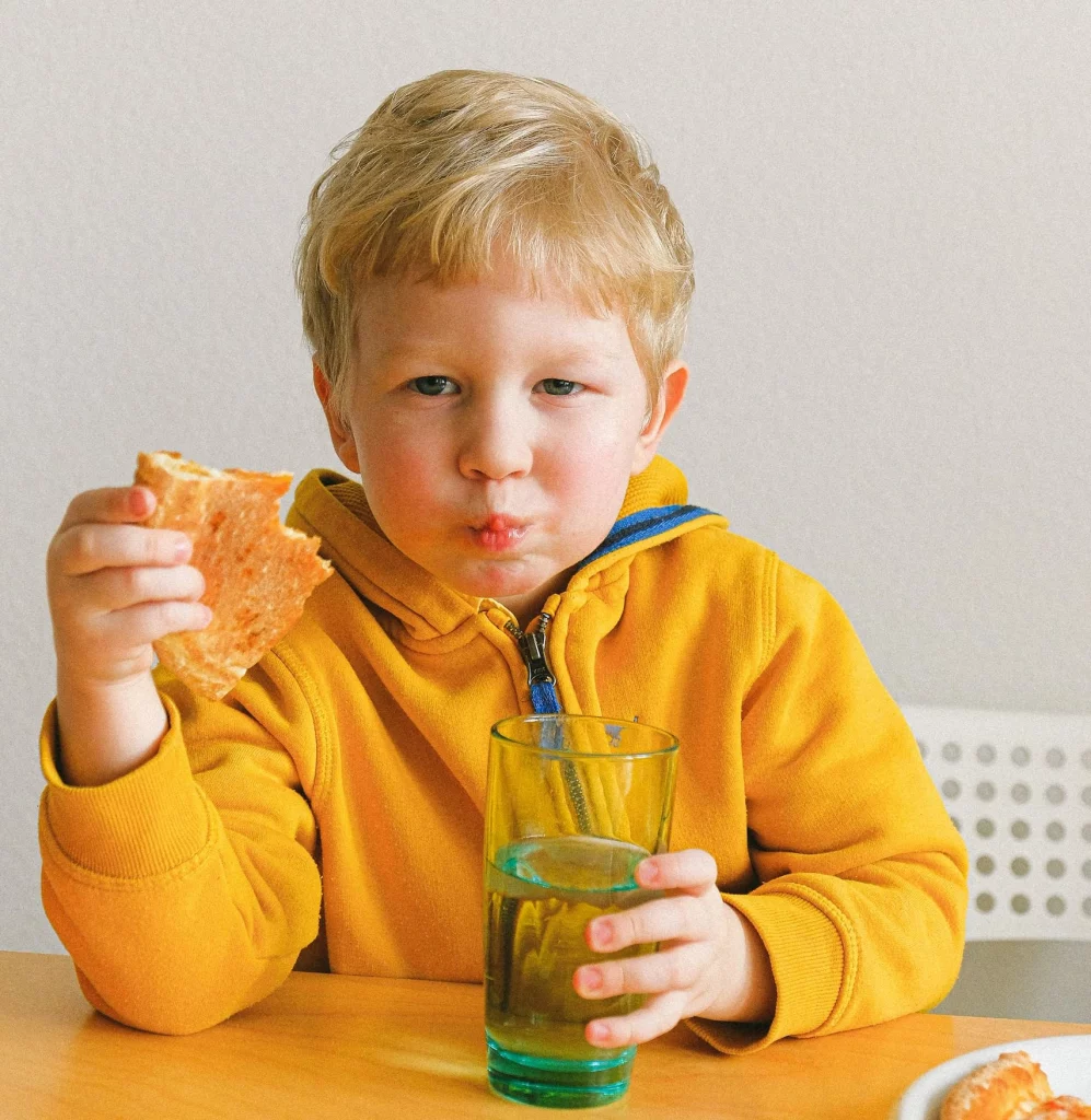 Das Kind isst eine Pizza, während die Mutter einen Nährstoffe Kurs besucht,